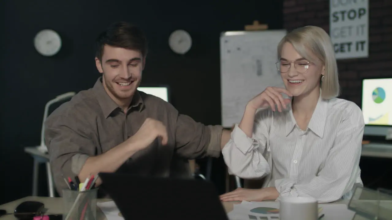 Business couple giving five in dark office Excited team celebrating success