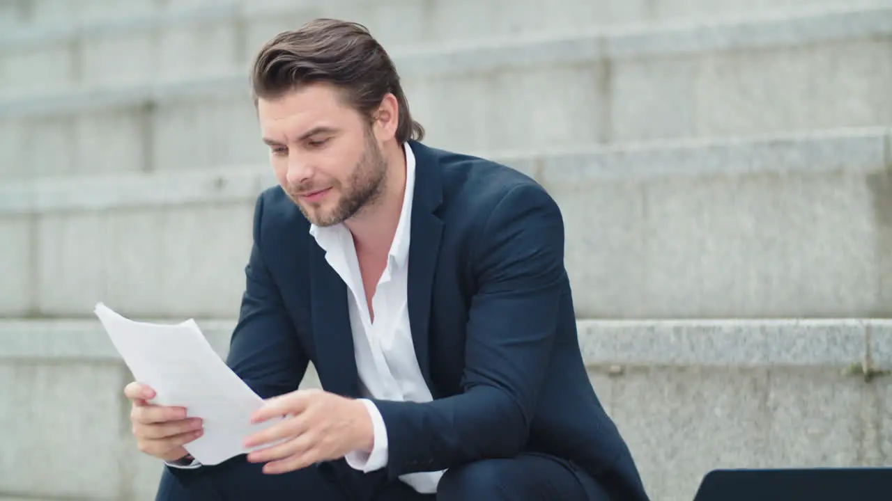 Businessman working with documents on street Man sitting on stairs