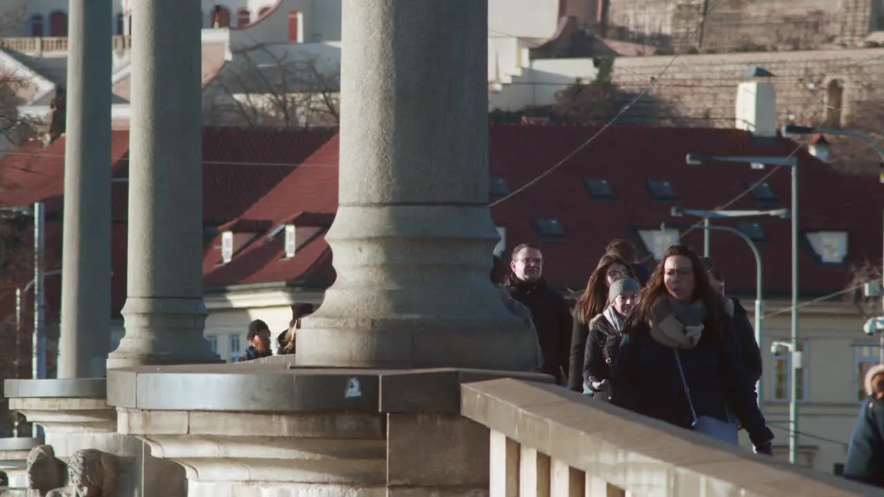 Pedestrians and tram cross conic Prague bridge on cold day slow-mo