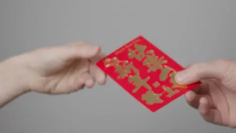 Close Up Shot of One Hand Taking a Red Envelope from Another On Chinese New Year