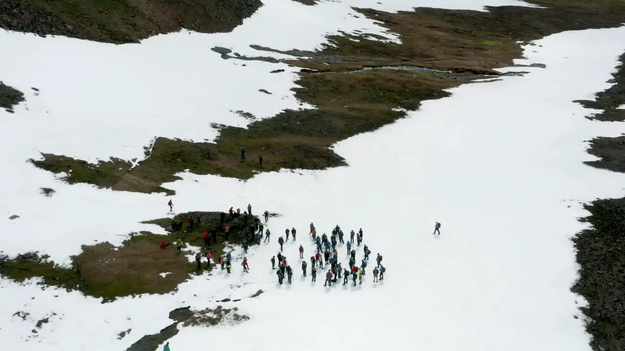 Group of people resting together during hike on snowy slope in Iceland