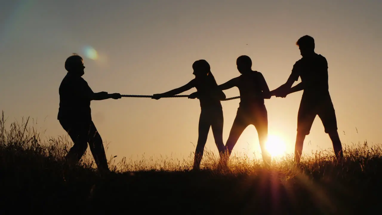 A Strong Older Woman Is Competing With Young People In Tug-Of-War Active Elderly People