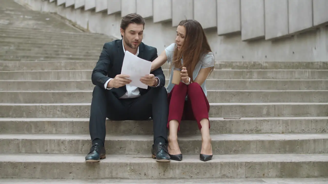 Smiling businessman and businesswoman discussing documents on urban street