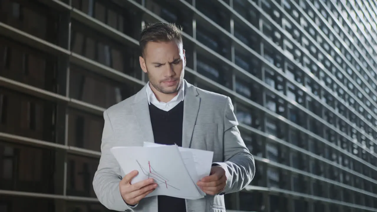 Executive reading documents on city street Businessman examining papers oEtside