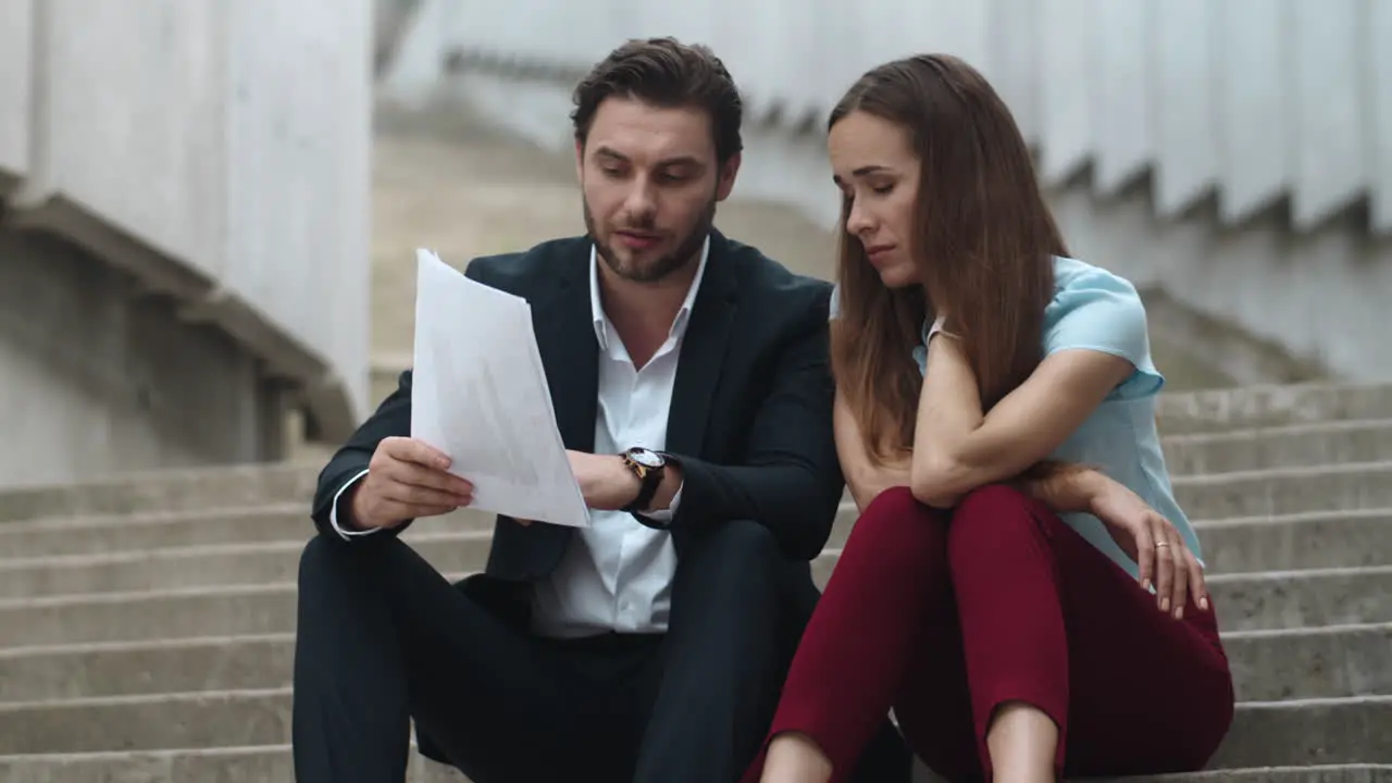 Tired business man and business woman looking at business papers on street