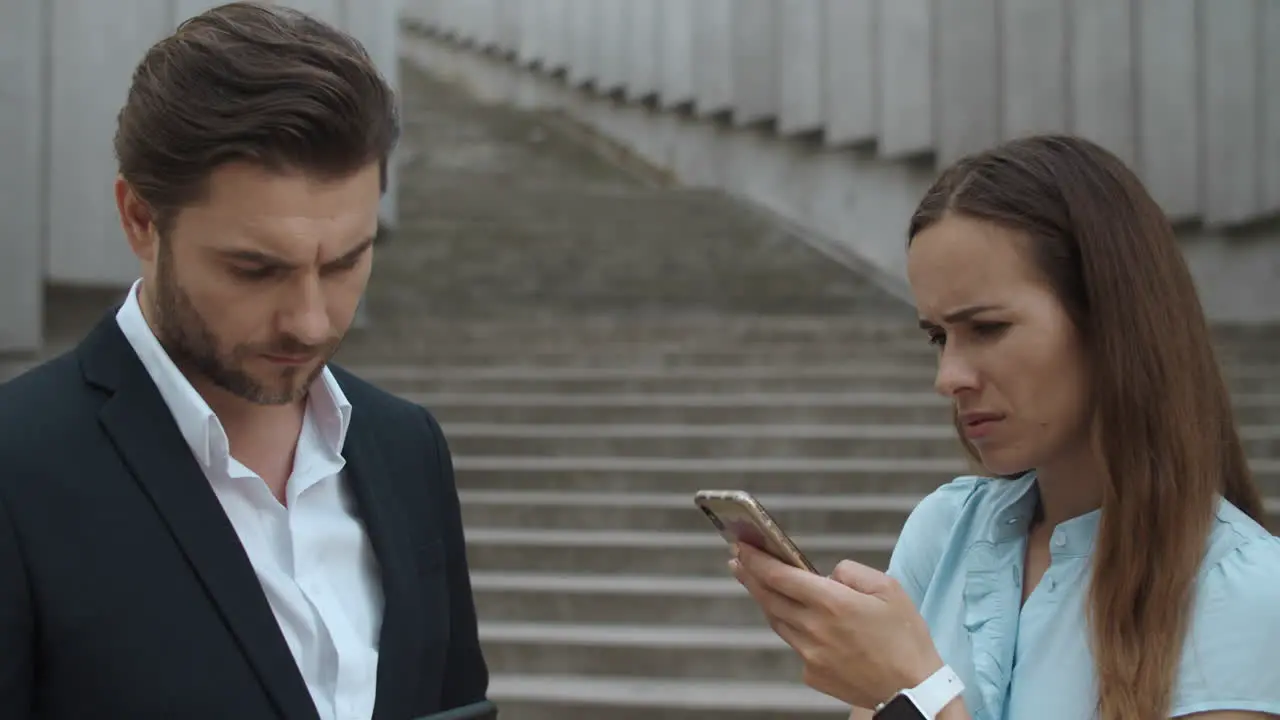 Man and woman standing on street Business couple using smartphones