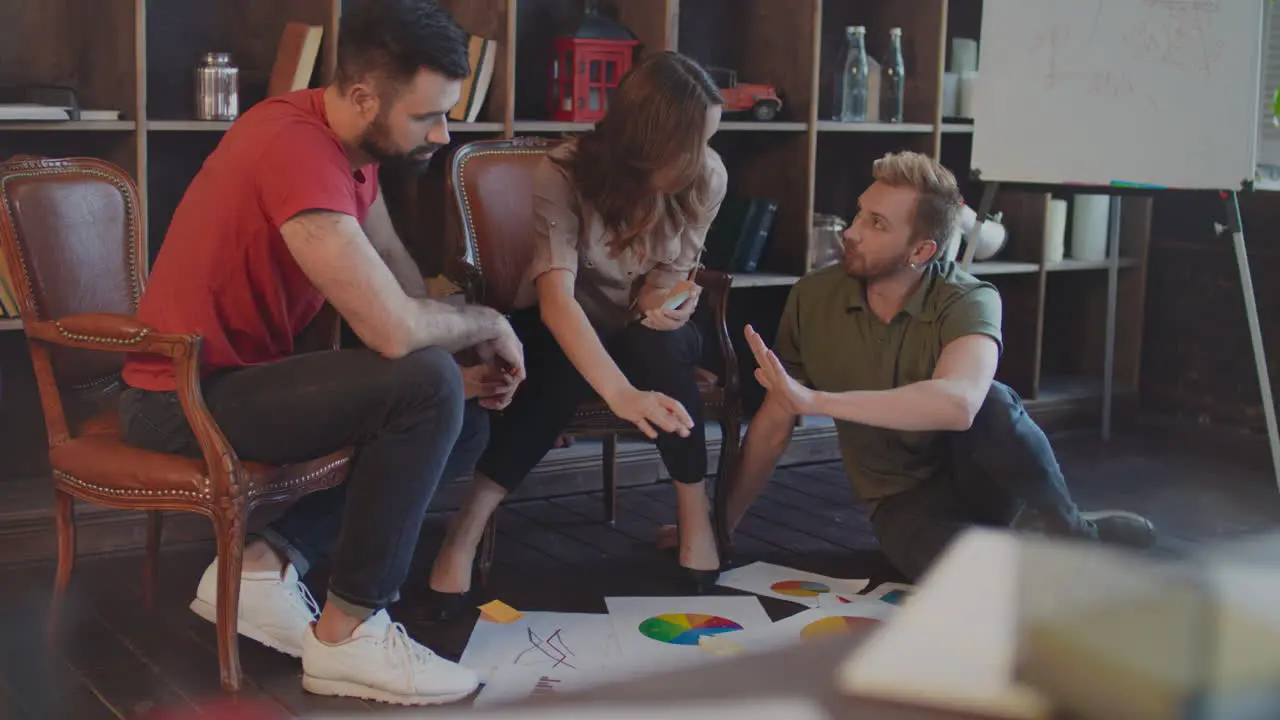 Creative business people discussion market graph on floor in cozy studio