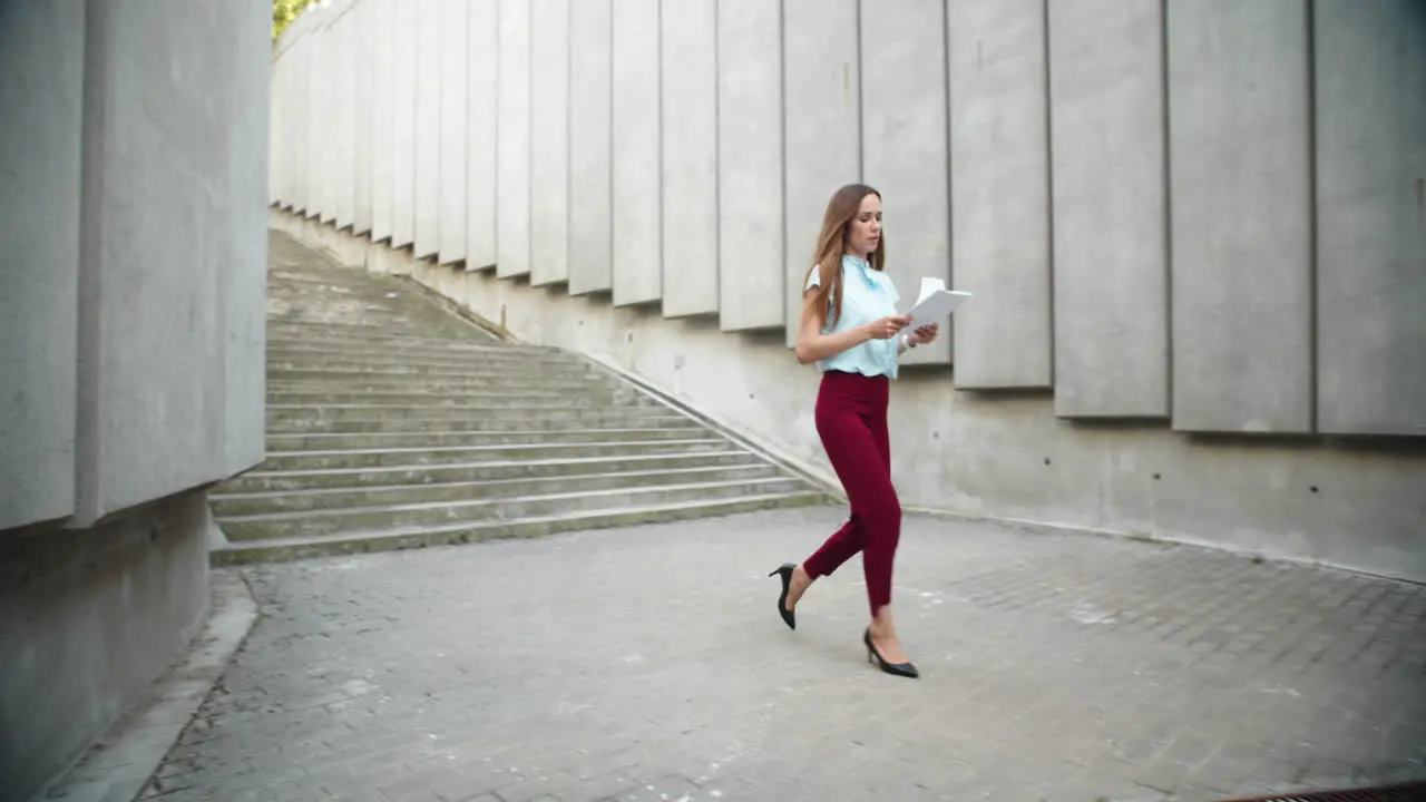 Businesswoman reading business documents outdoors Female worker walking for job