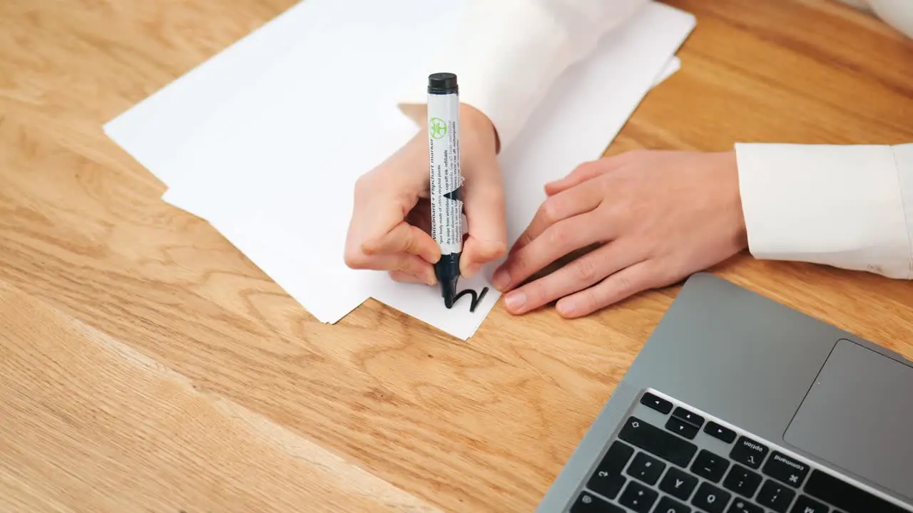 Woman hand drawing with black pen on sheet of paper at modern desk in the office