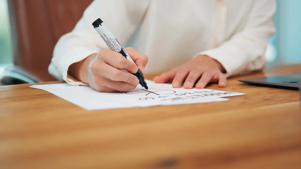 Woman drawing marketing business model with black pen on sheet of paper at modern wooden office desk