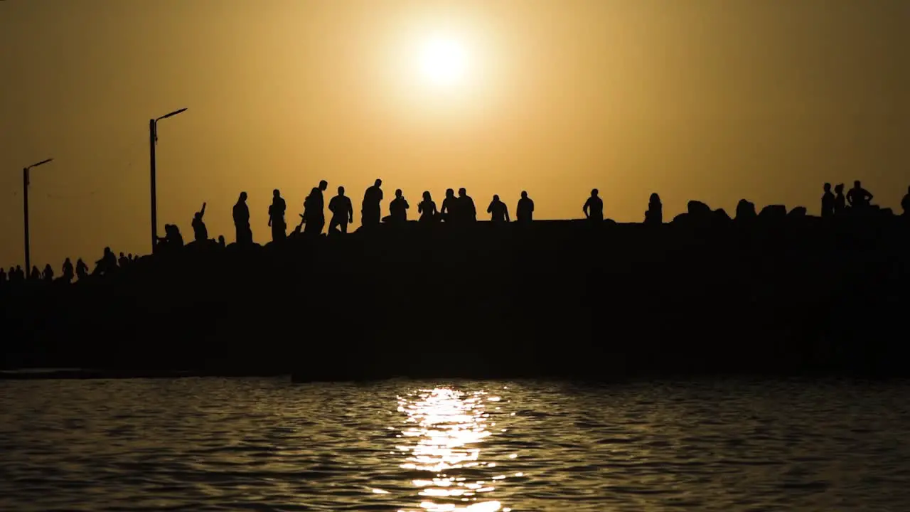 Silhouette of Group of People walking on the sea dock at sunset