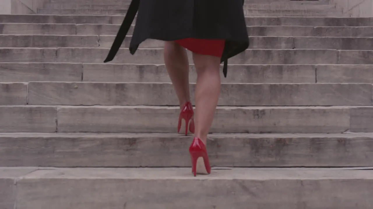 A woman climbs concrete steps in a city