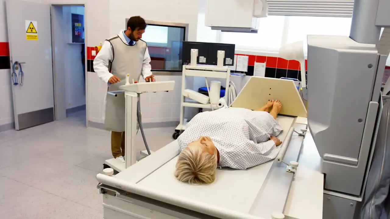 Male doctor sets up the machine to x-ray a female patient