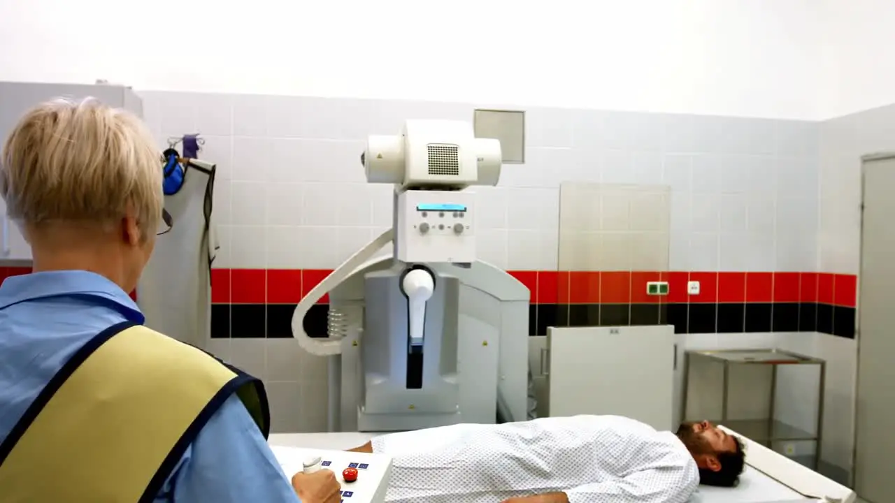 Female doctor sets up the machine to x-ray a male patient