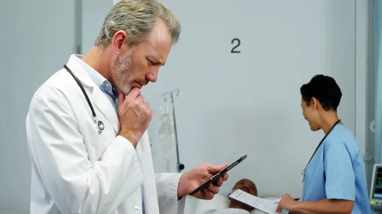 Doctor using digital tablet while nurse interacting with patient