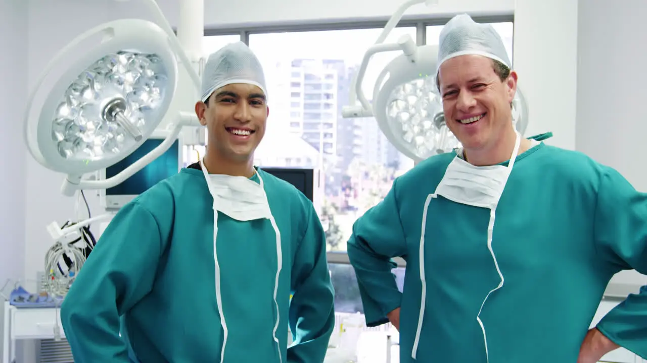 Portrait of male surgeons standing with hands on hips in operation room