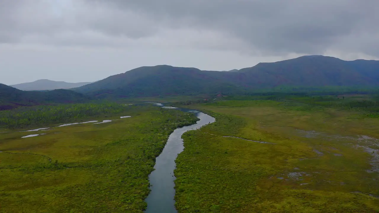 Drone shot traveling forward above vast empty lands scattered with some lakes and rivers with some mountains