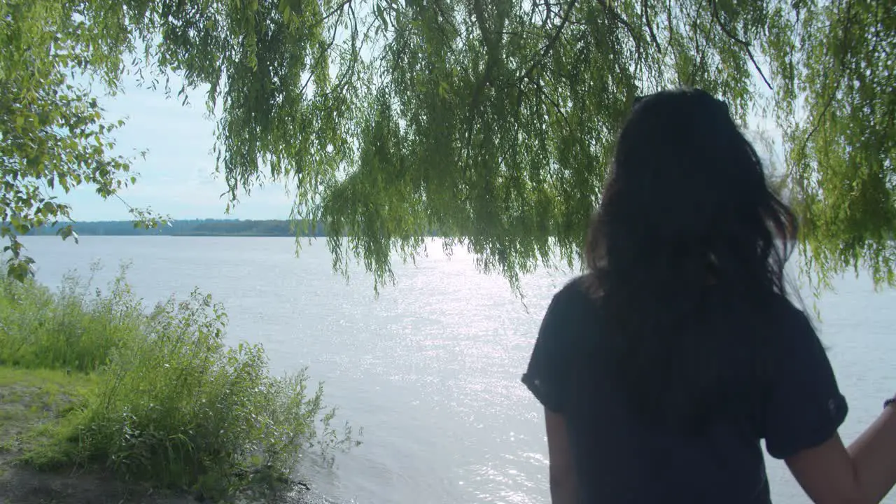 Woman beside a tree looking into a vast river