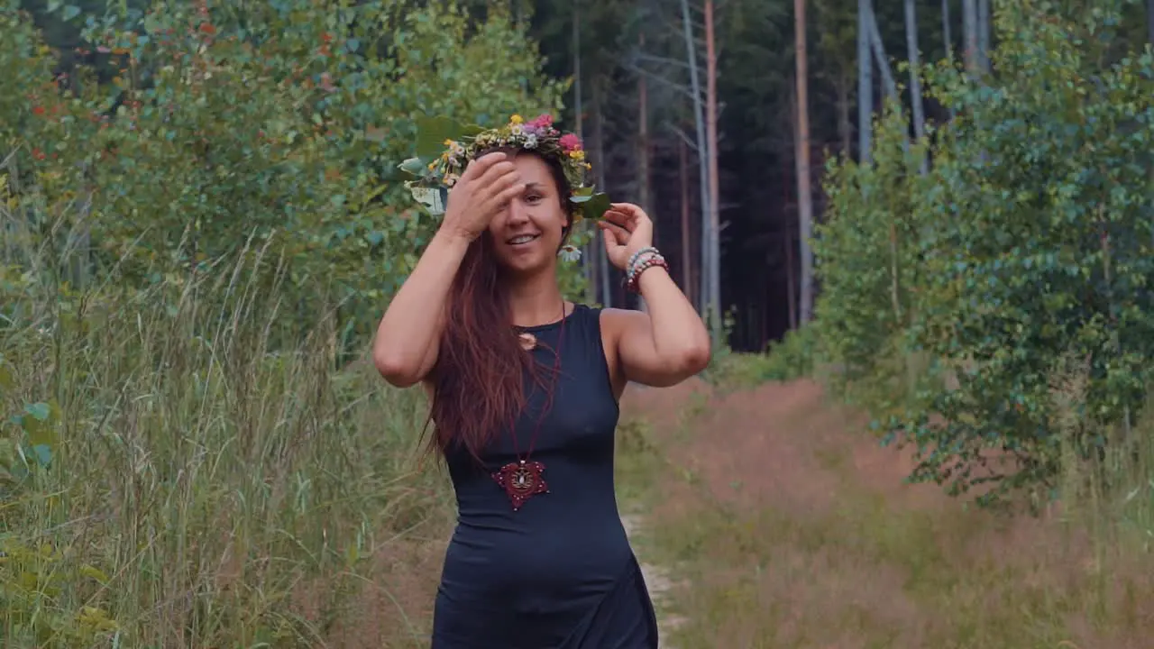 A pretty young happy girl smiling and walking towards camera in nature during an outdoor shoot in the forest between trees 