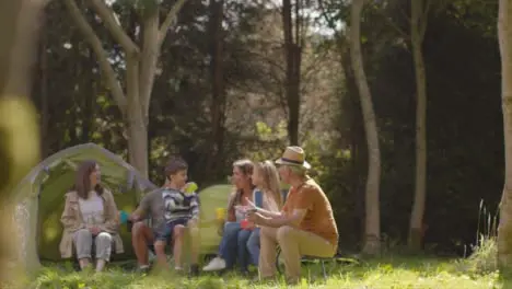 Long Shot of Family On Camping Trip Sitting By Their Tents 02