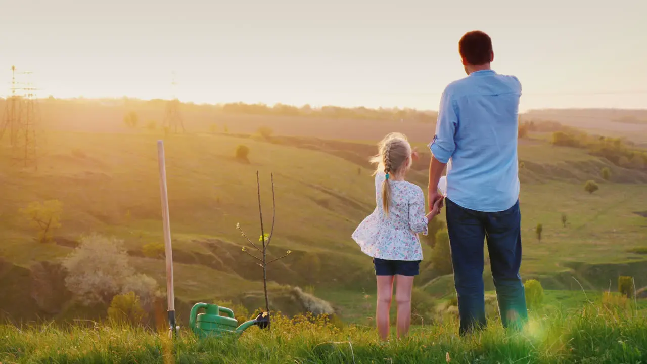 The Father And Daughter Together Look Forward To The Horizon Where The Sun Sets