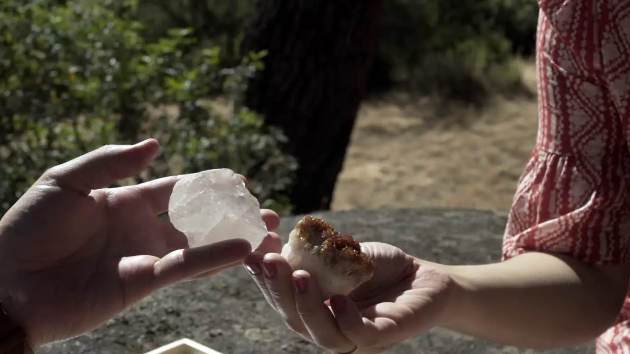 Man is looking at a rock that looks like white crystals while a girl is looking at another rock that has brown silt features that are dazzling and sparkly