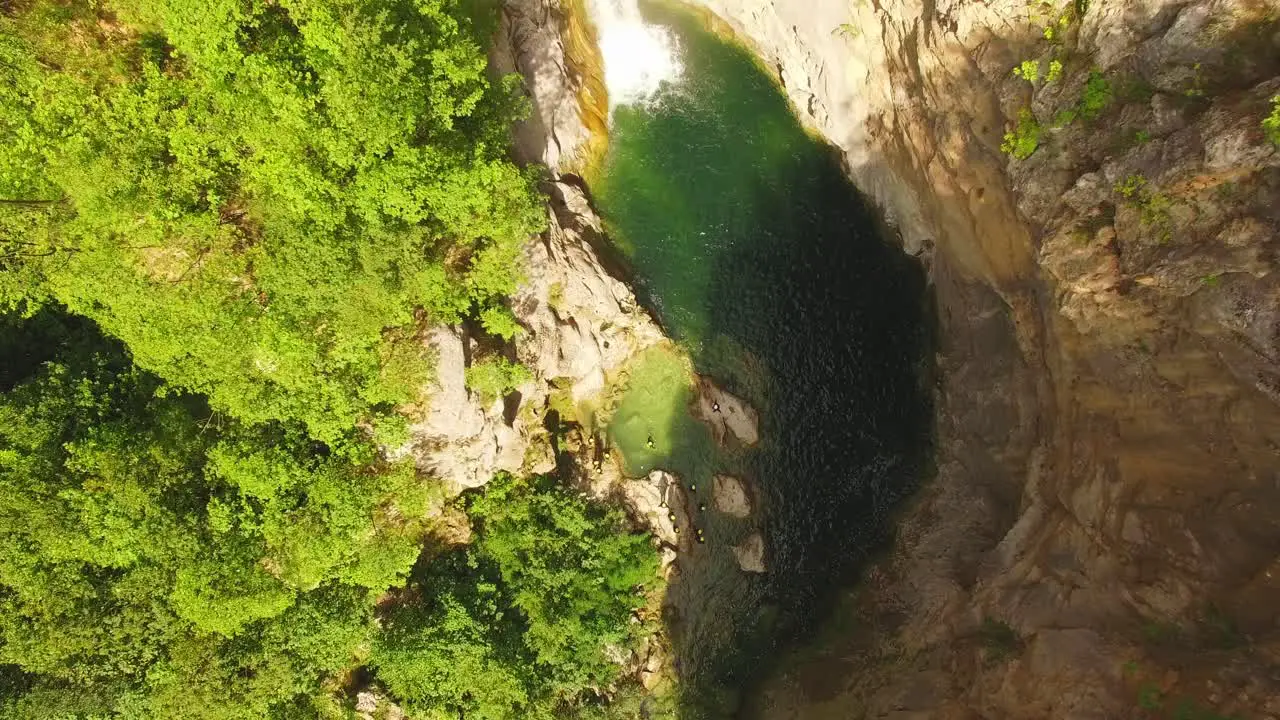 People swimming in river waterfall and rocks around them