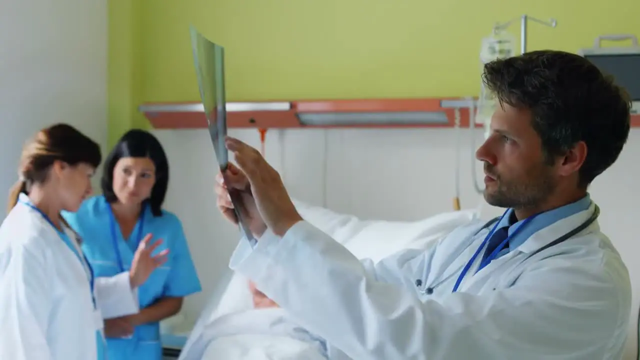 Doctor examining x-ray while nurse interacting with patient in background