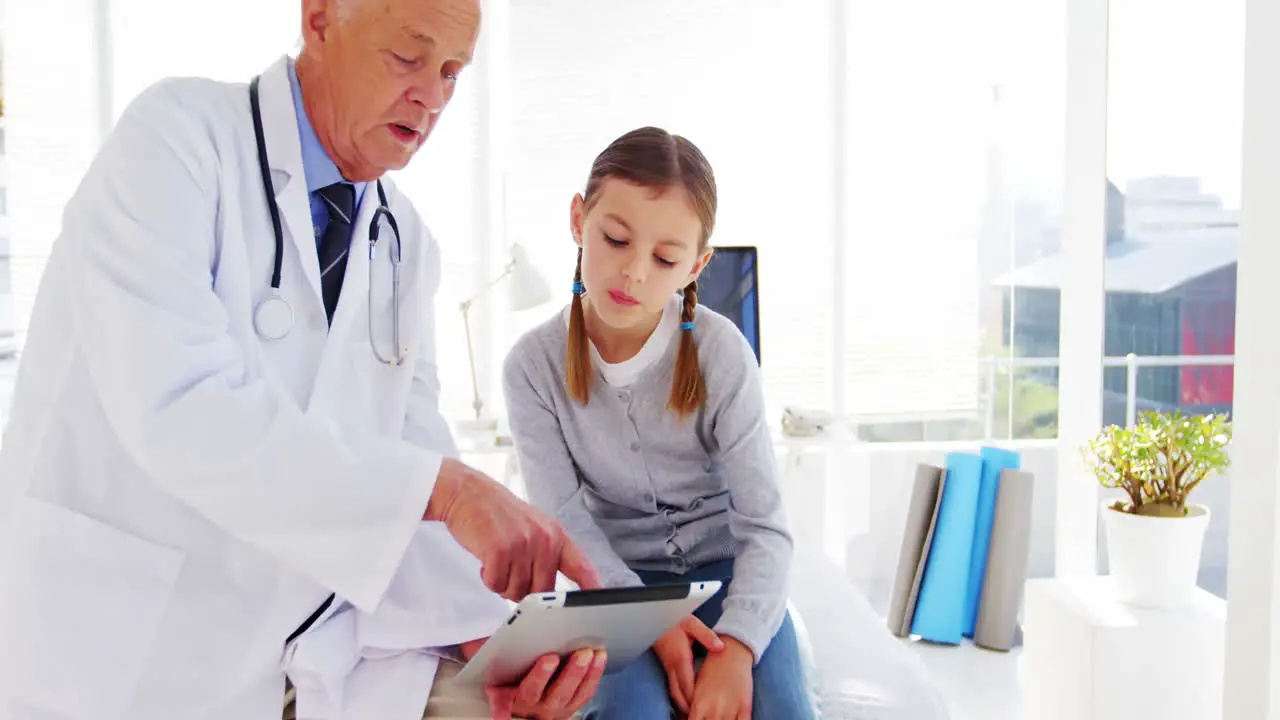 Male doctor discussing with girl over digital tablet