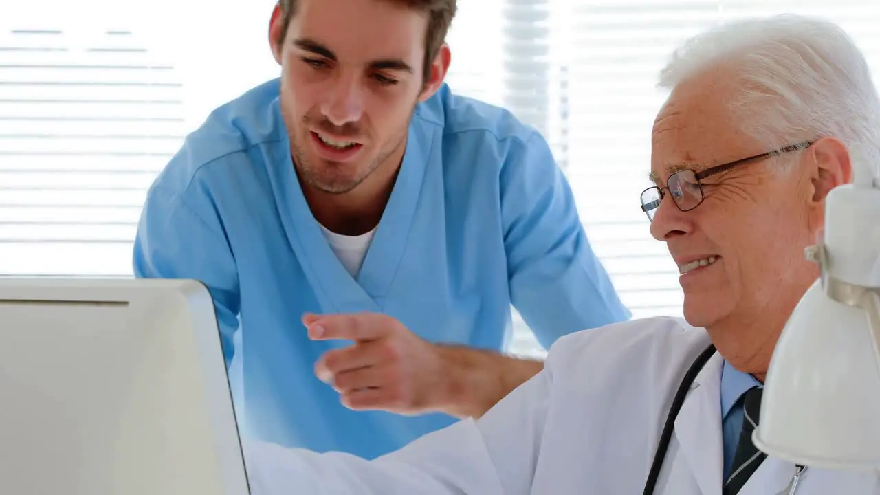 Doctor interacting with his colleague while working on computer