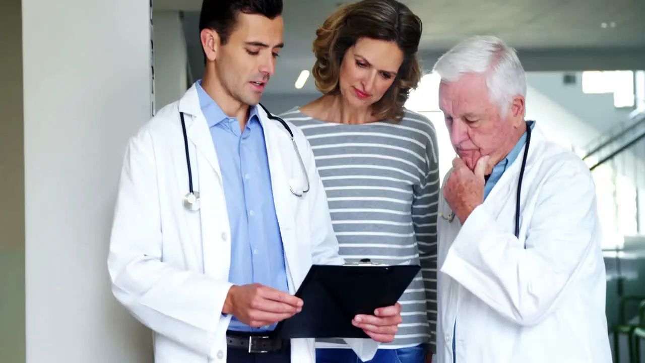 Mother and doctors discussing over clipboard