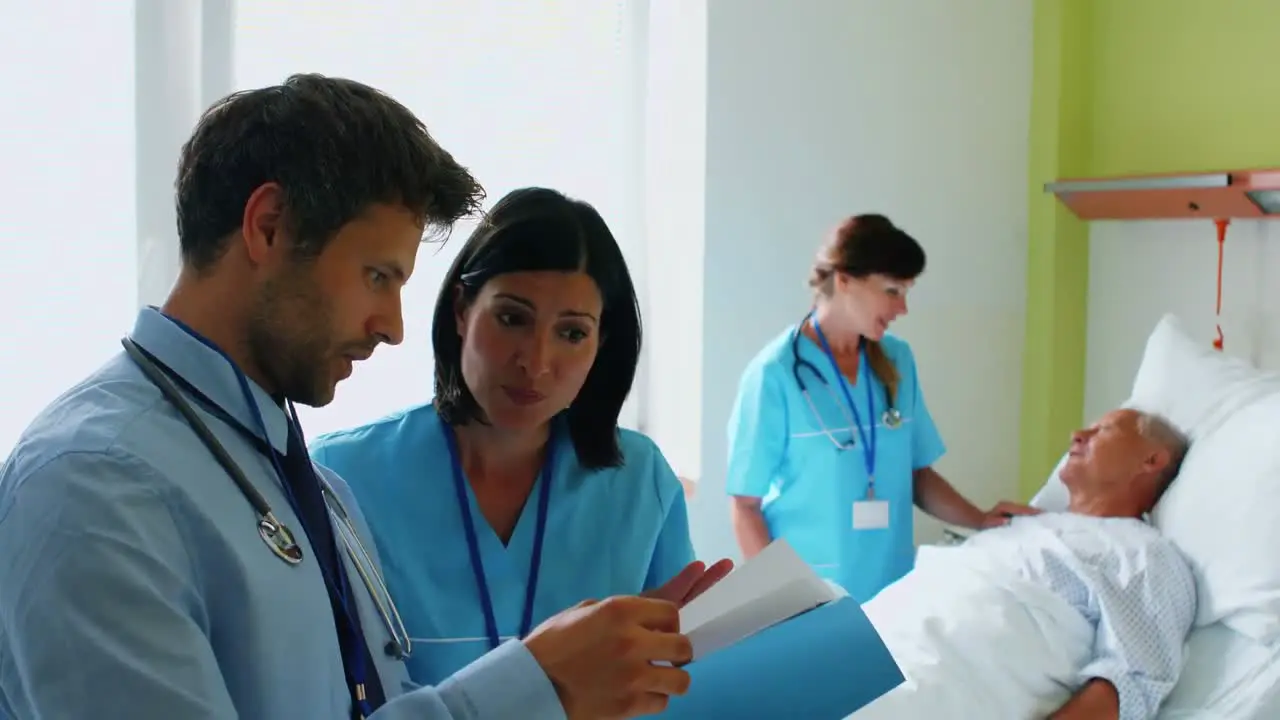 Doctors discussing on reports while nurse interacting with patient in background