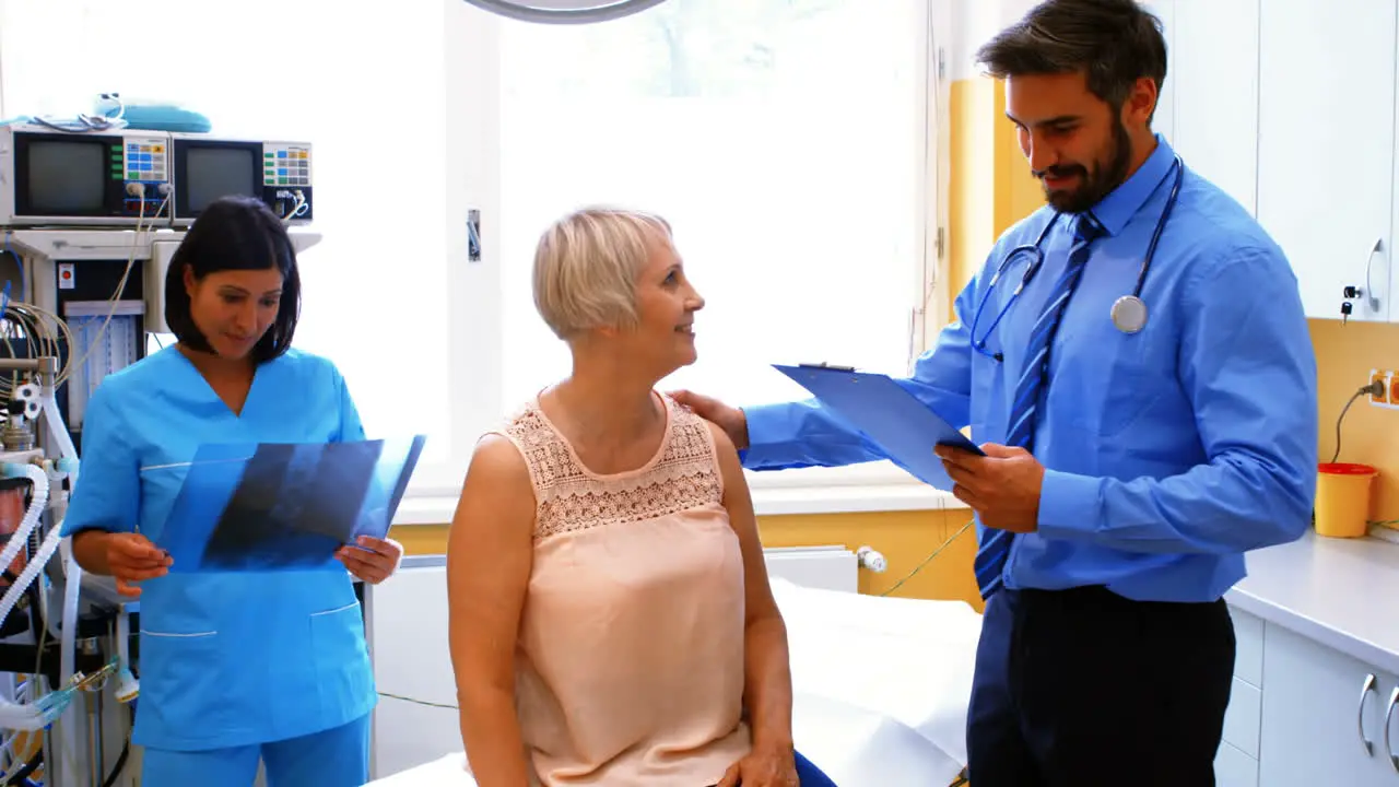 Male doctor interacting with a patient while nurse looking at x-ray