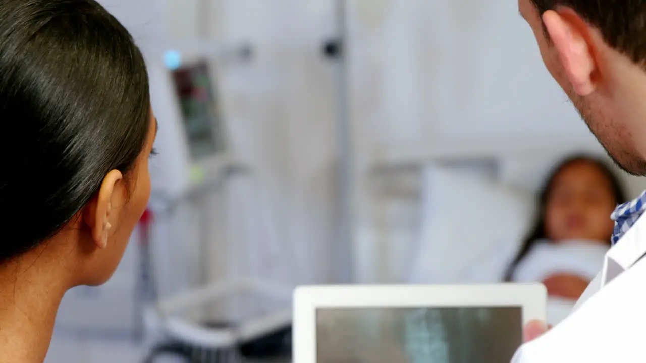 Doctor and nurse looking at x-ray report on digital tablet