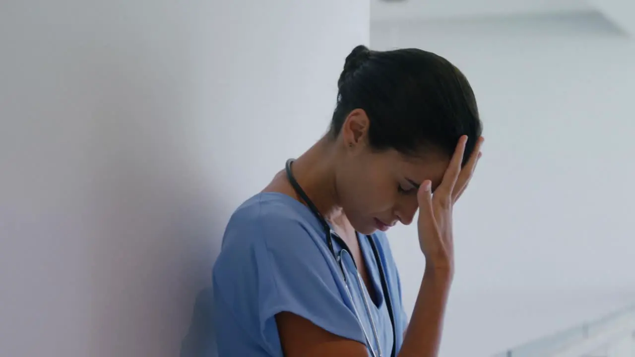 Sad female surgeon standing in corridor