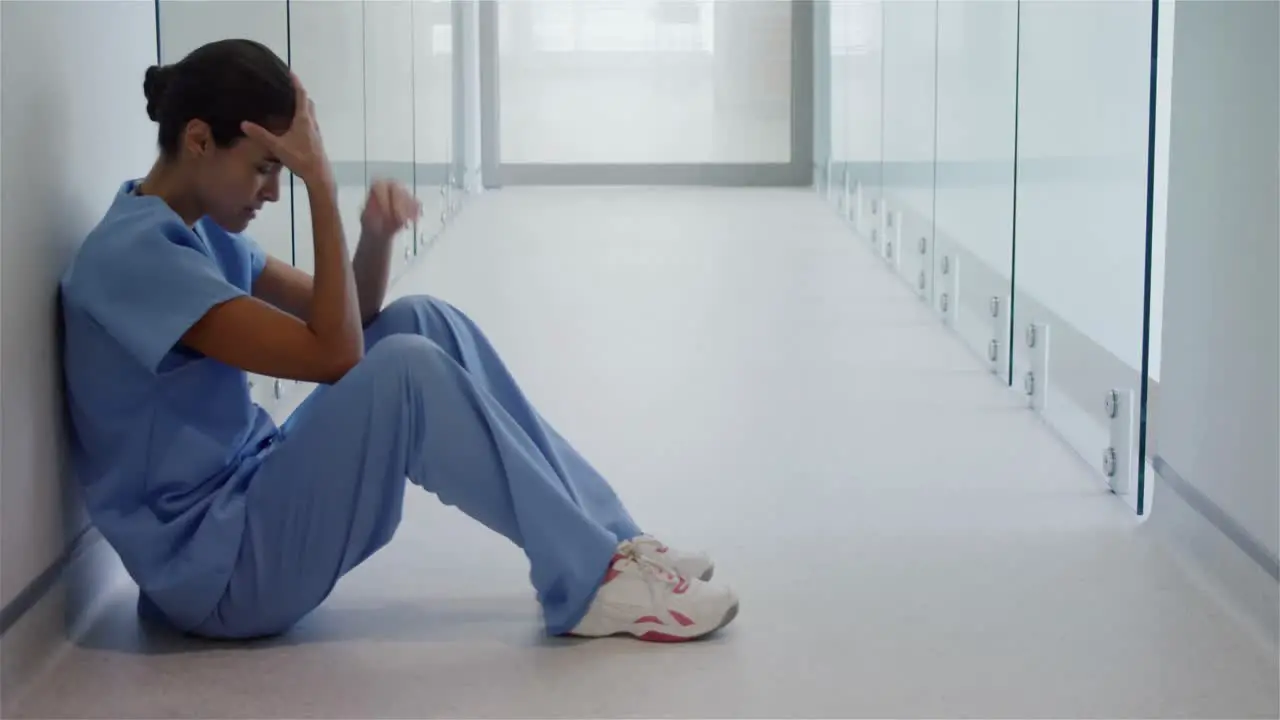 Sad female surgeon sitting in corridor