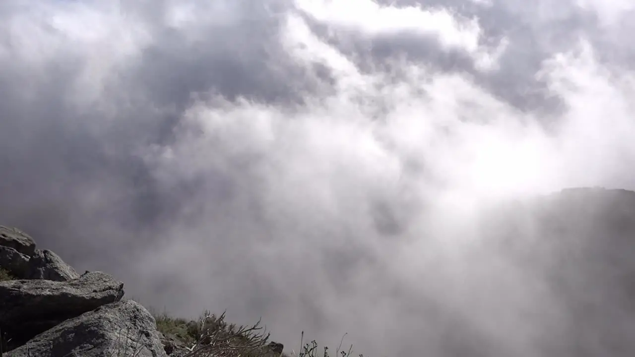 Low flying clouds floating up a rocky surface