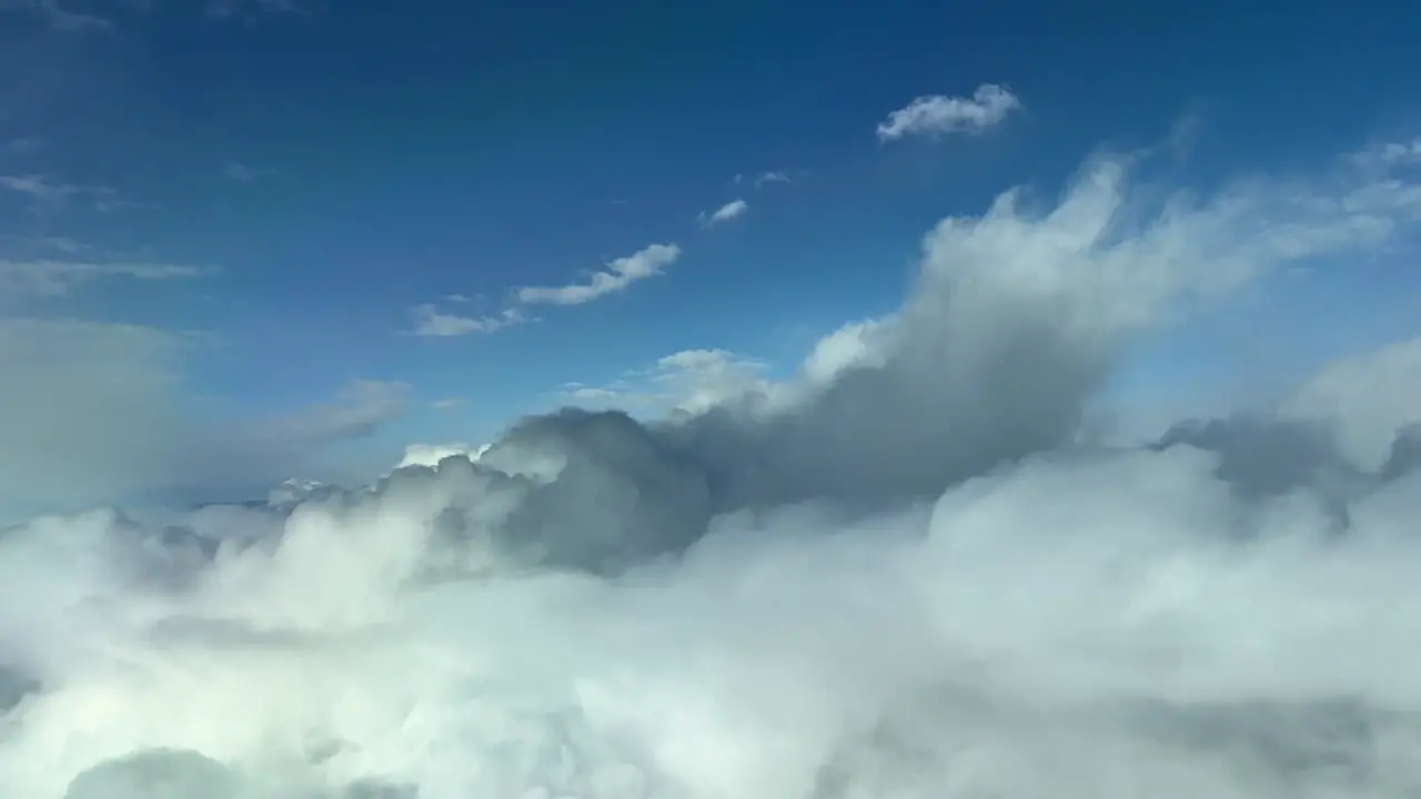 Aerial view from a cockpit flying trough white and grey clouds