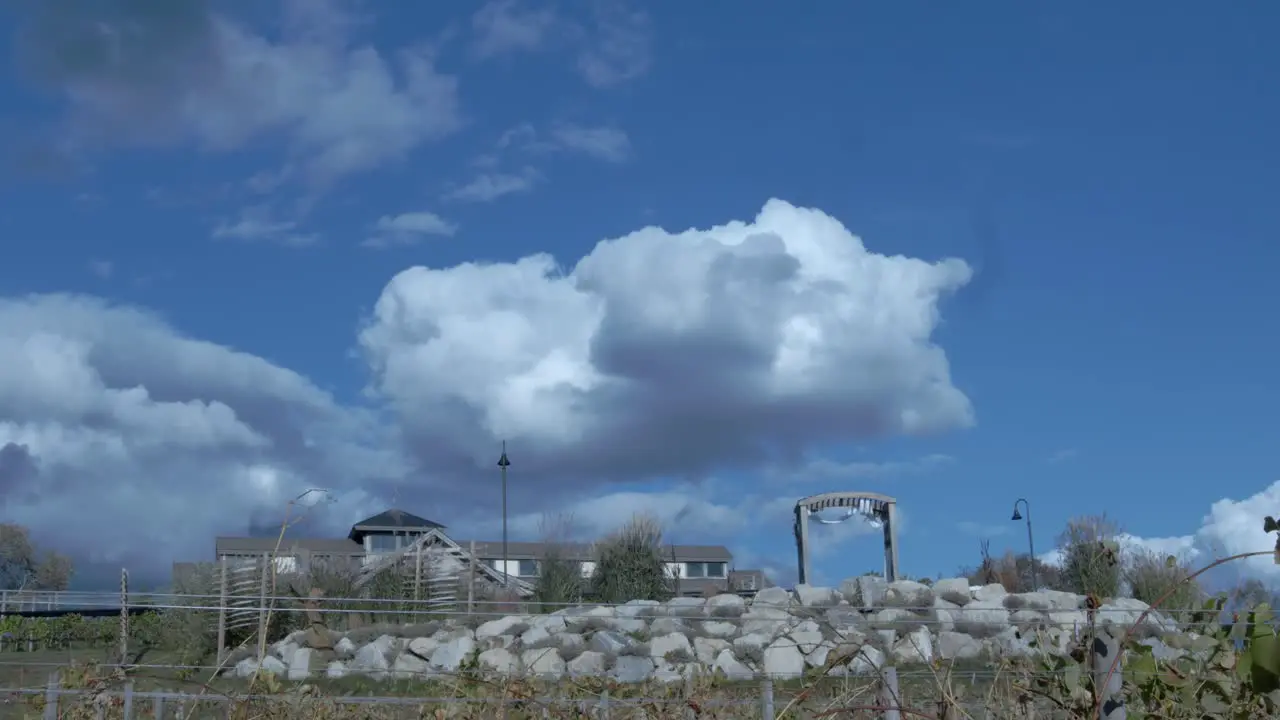 A winery sits atop a stone wall against a beautiful cloudy blue sky