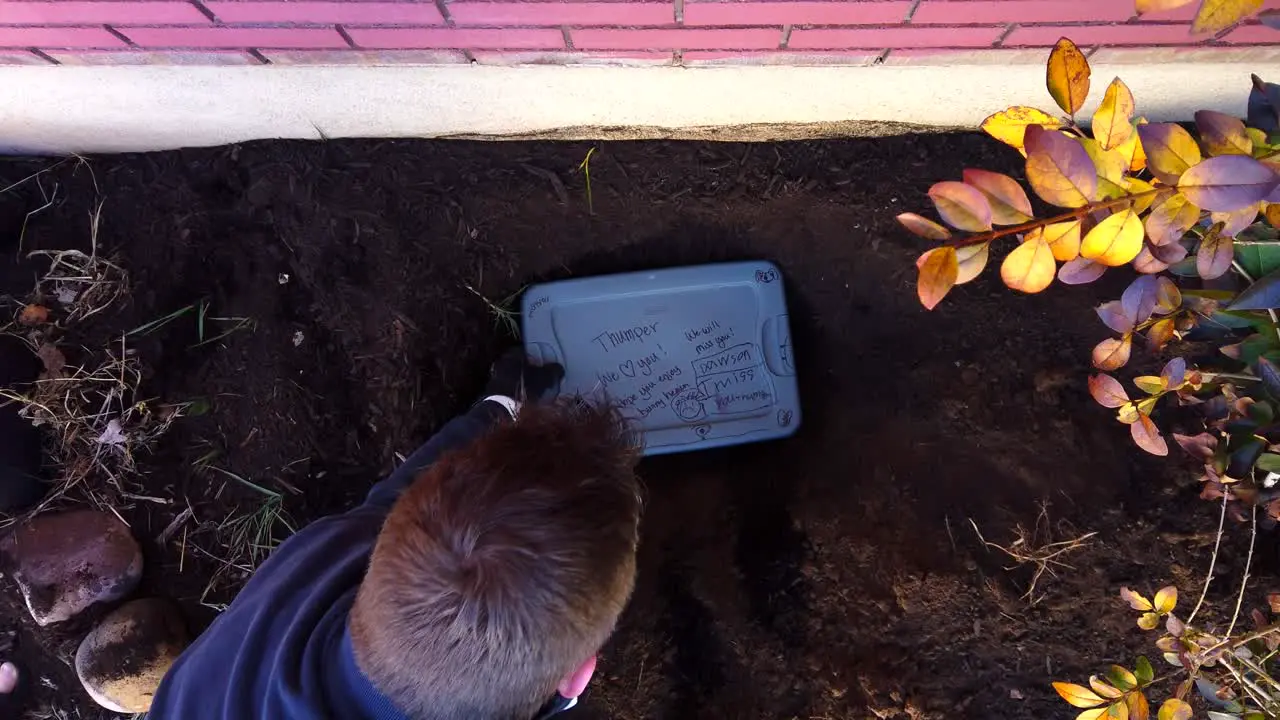 Digging and measuring a dead house pet’s grave and hole in a flower garden