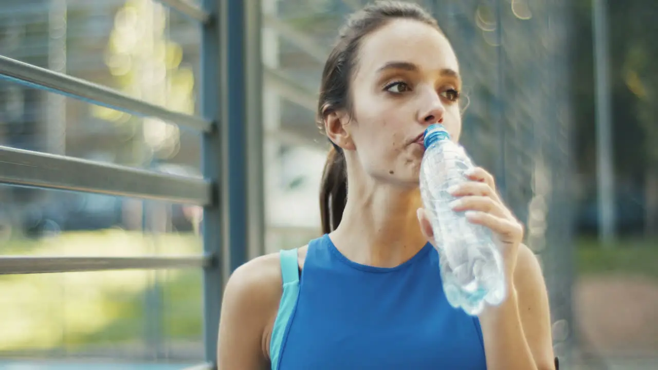 Sporty Woman Drinking Cold Water At Outdoor Court On A Summer Day