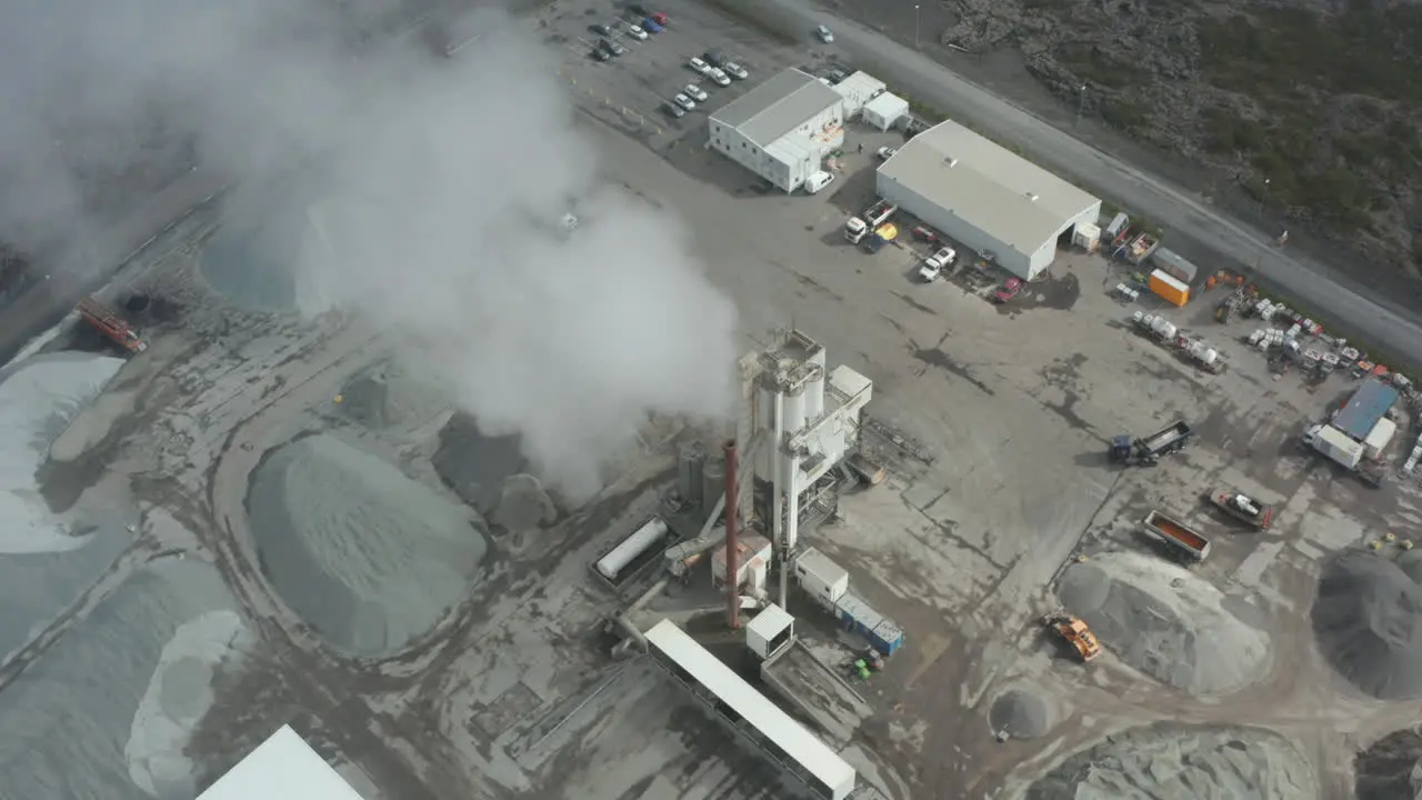 Drone view orbit around the central establishment of Colas in Iceland Aerial view of asphalt industry with establishment and machinery and piles of material