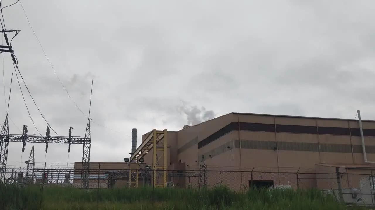 Steam rising from a steel plant gray skies brick building railroad tracks