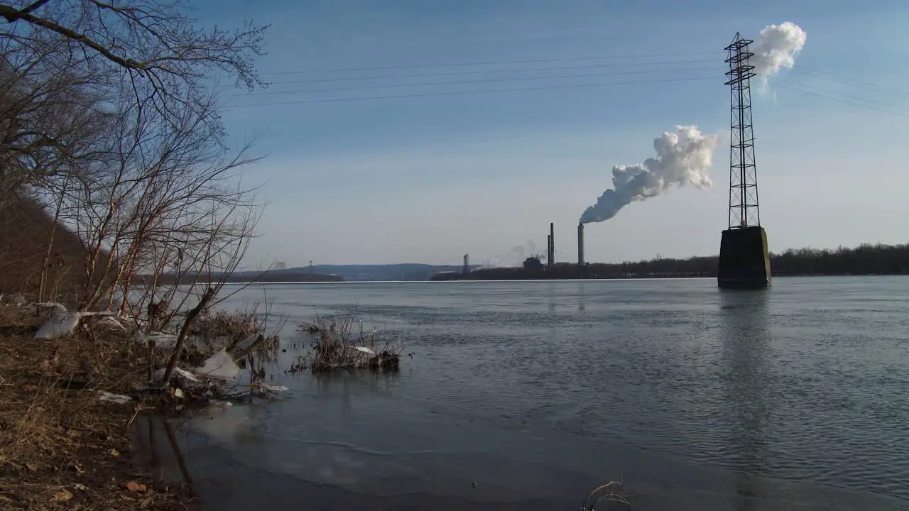 Smoke rises from a distant power plant along a river