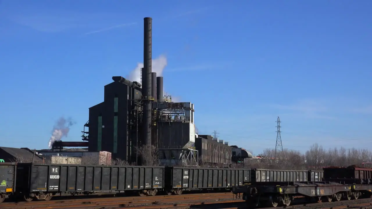 Global warming is suggested by shots of a steel mill belching smoke into the air with railcars foreground 1