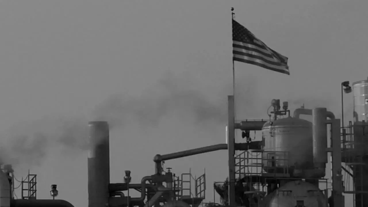 Smoke moves across the sky in an industrial area in a black and white shot