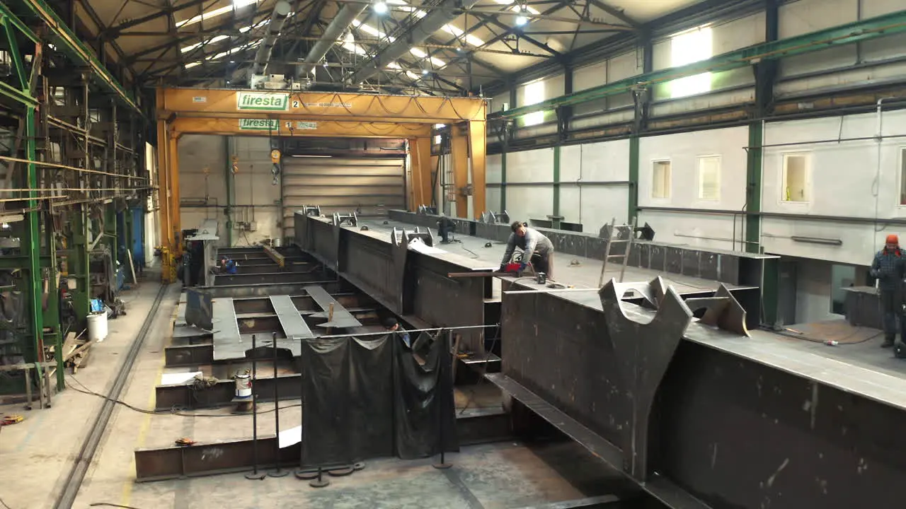 Workers assembling steel bridge in industrial steelwork factory hall