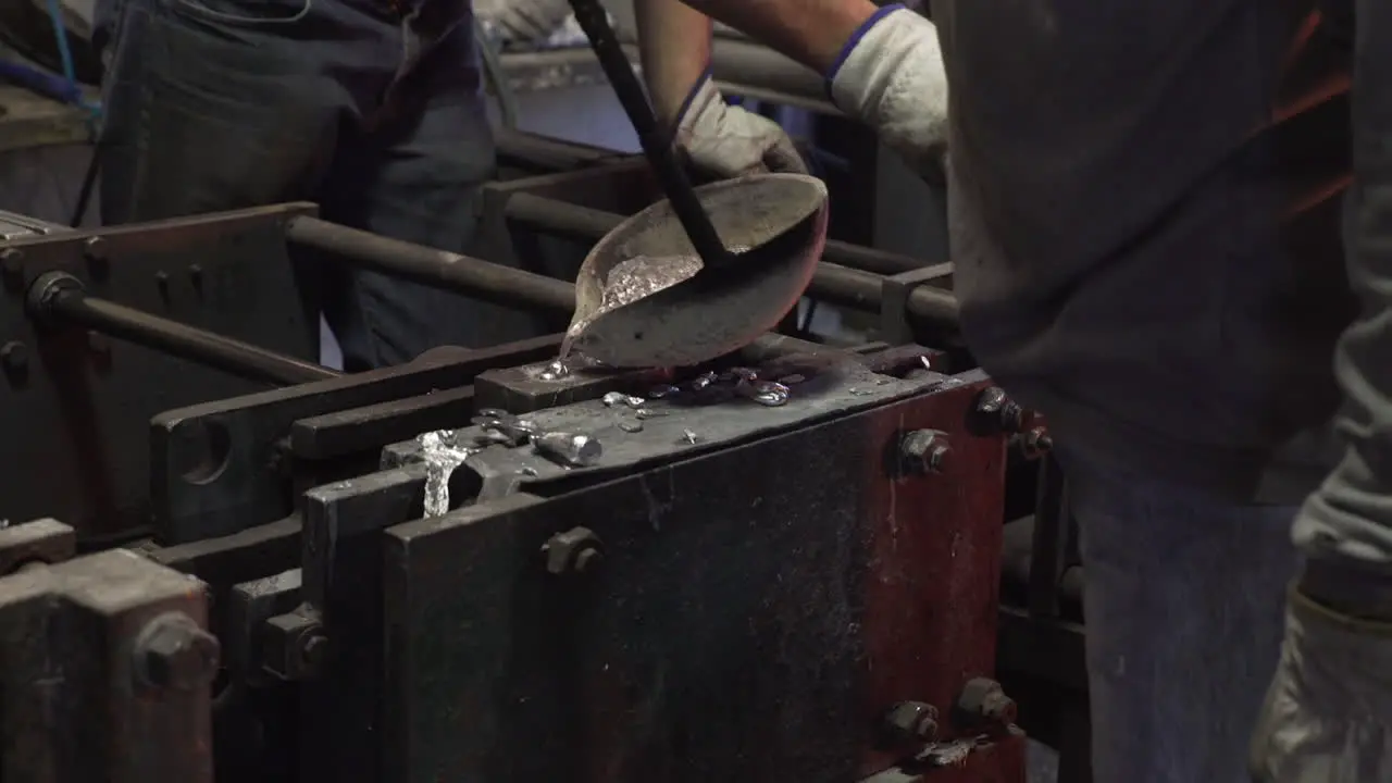 People pouring melted metal into casts in a factory