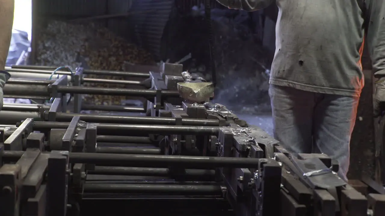 Side view of people pouring liquid metal into casts in a factory