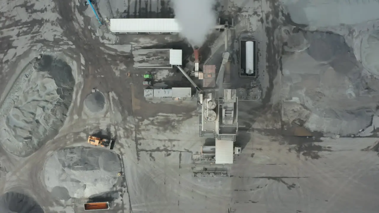 Top down drone view flying over an asphalt industry Overhead view showing machinery establishment and pile of raw material